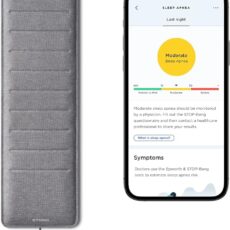 Grey Withings Sleep Analyzer pad partially visible under a mattress corner, with a smartphone displaying sleep data nearby.